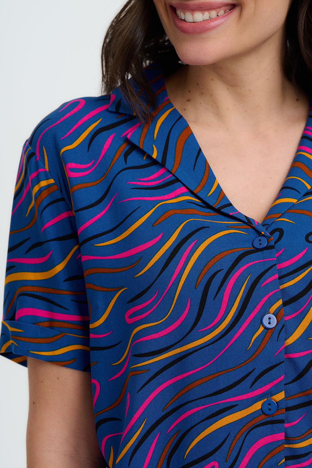 Woman wearing a colorful patterned shirt with a blue background