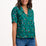 Sugarhill Brighton model wearing a green polka dot blouse and blue jeans on a white background