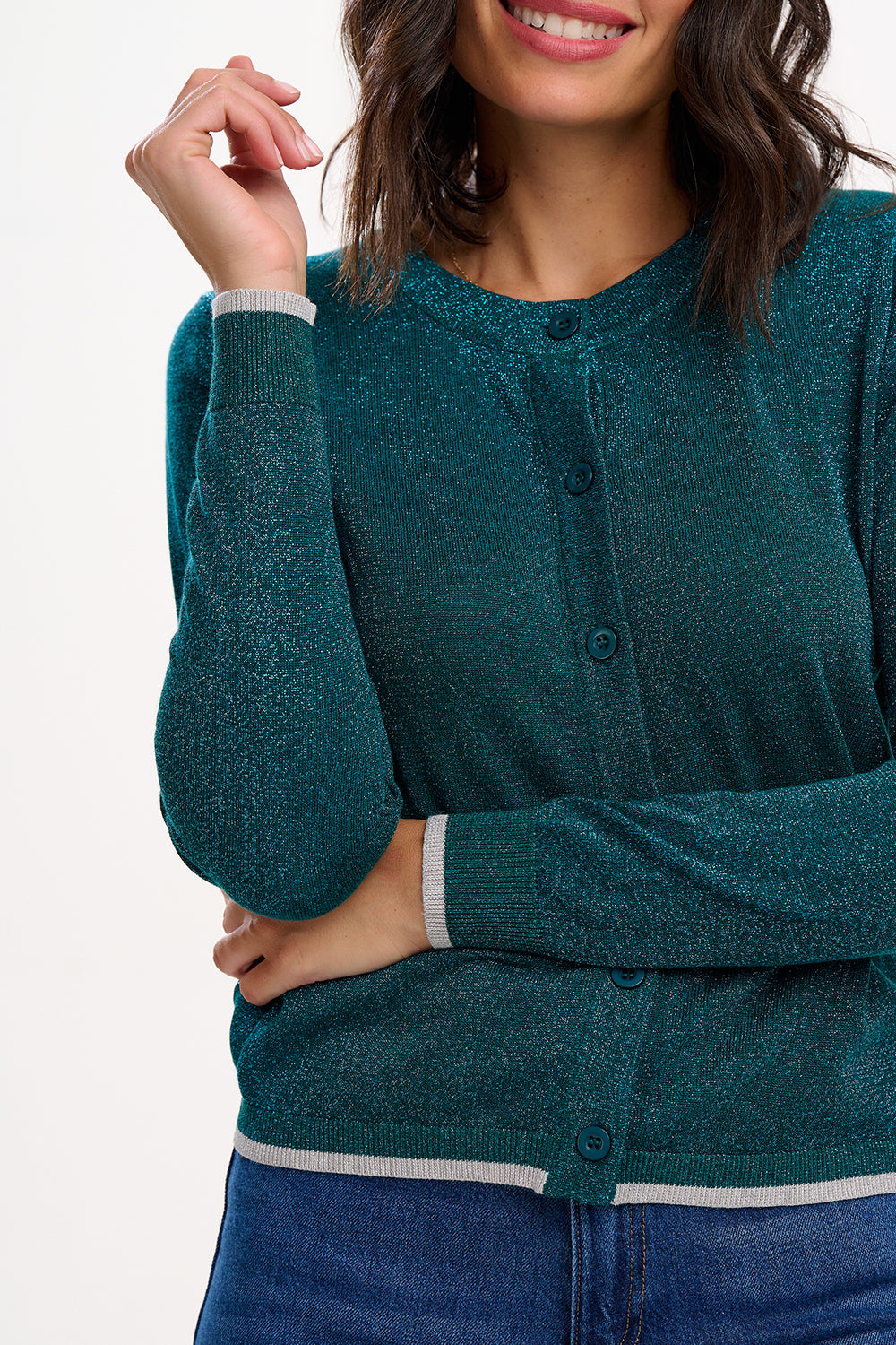 Woman wearing a teal cardigan with white trim on a plain background