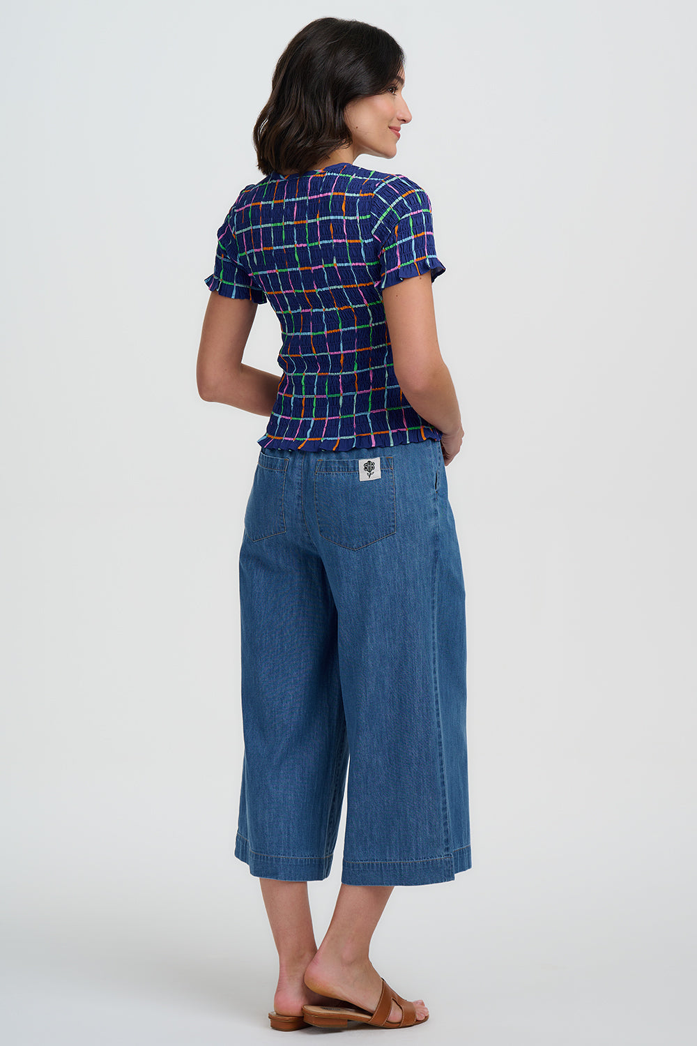 Woman wearing a blue plaid shirt and denim pants on a white background