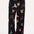 A model wearing black palazzo pants with a vibrant tropical parrots print standing against a white background.