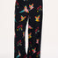 A model wearing black palazzo pants with a vibrant tropical parrots print standing against a white background.