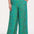 A woman modeling green palazzo pants with a multicolored dot pattern, paired with a white t-shirt.