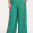 A woman modeling green palazzo pants with a multicolored dot pattern, paired with a white t-shirt.