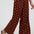 Brown wide-leg pants with pink polka dots worn by a person on a white background