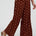 Brown wide-leg pants with pink polka dots worn by a person on a white background