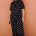 Person wearing a black polka dot jumpsuit against a brown wall