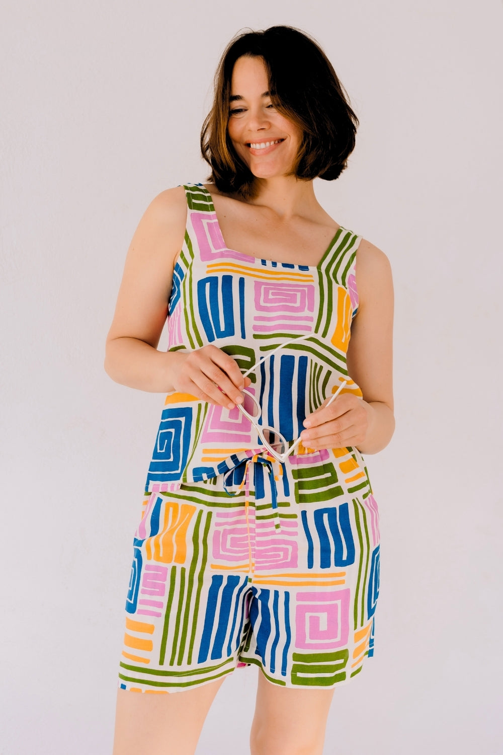 Woman wearing a colorful patterned romper against a plain background