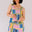 Woman wearing a colorful patterned romper against a plain background