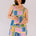 Woman wearing a colorful patterned romper against a plain background