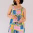 Woman wearing a colorful patterned romper against a plain background