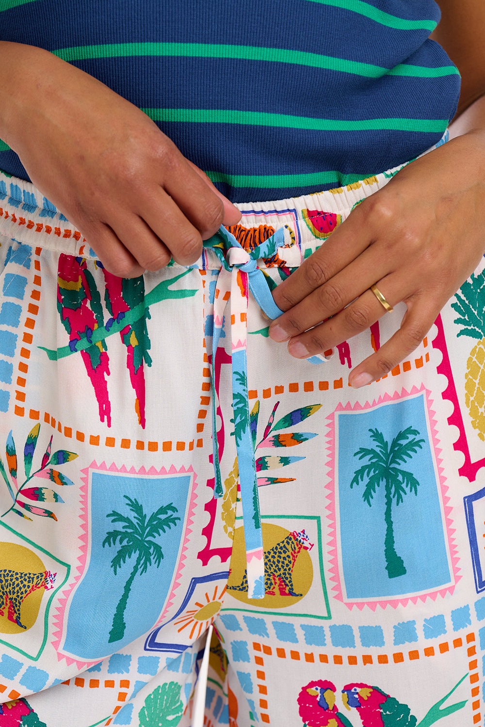 A woman standing, wearing off-white shorts with a multicolor jungle tile print,