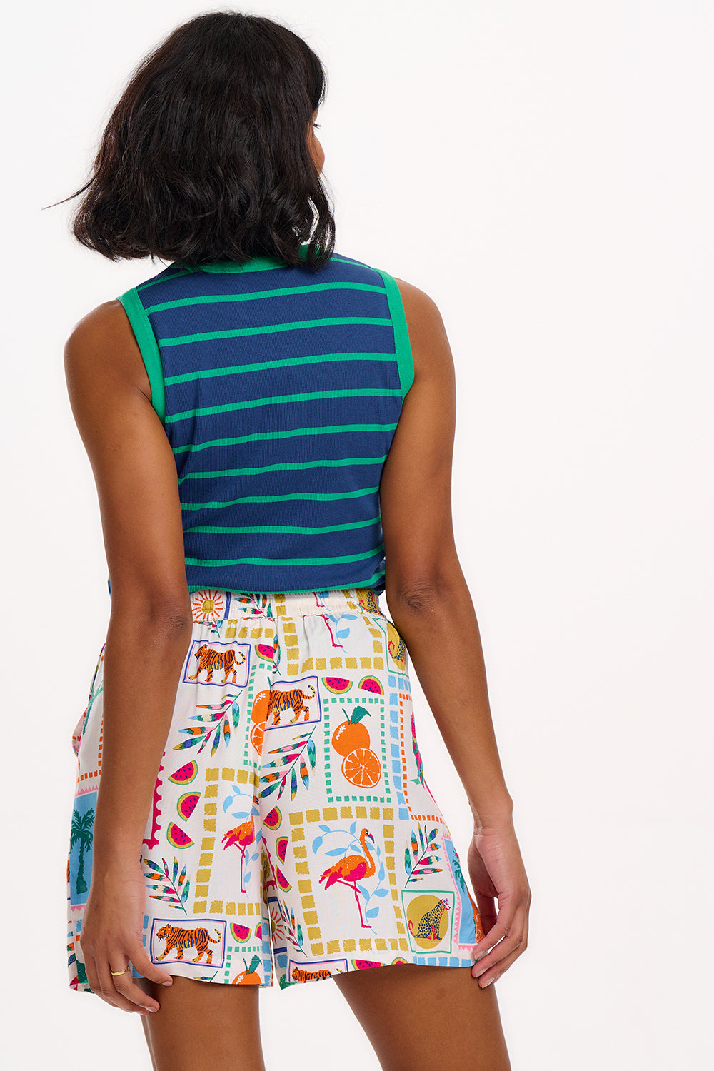 A woman standing, wearing off-white shorts with a multicolor jungle tile print, 