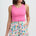 Woman wearing a pink tank top and colorful patterned shorts on a white background