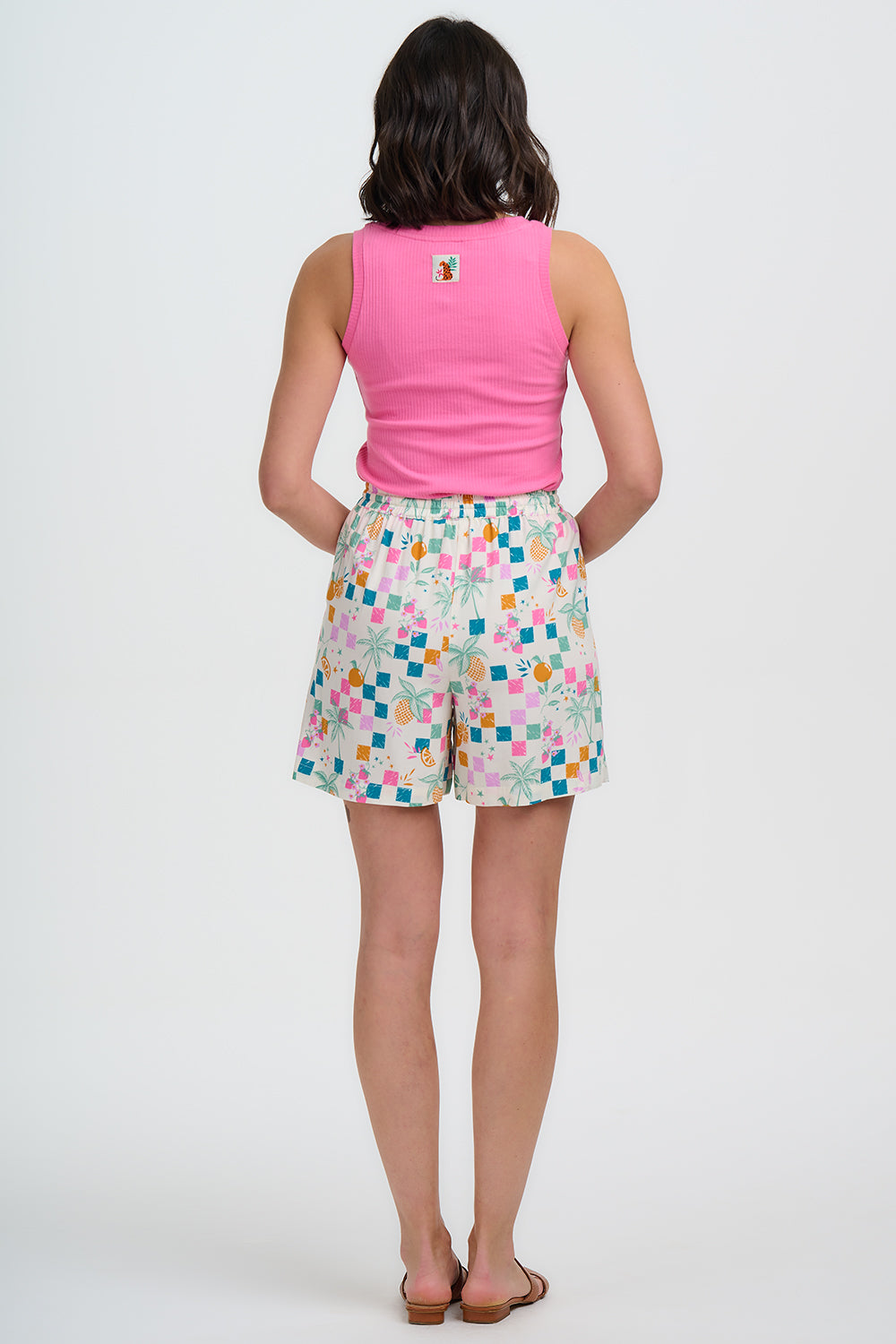 Woman wearing a pink sleeveless top and colorful patterned shorts on a white background