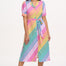 A model wearing a midi length shirt dress with a button placket and puff sleeves, featuring a multicolor rainbow checkerboard pattern.