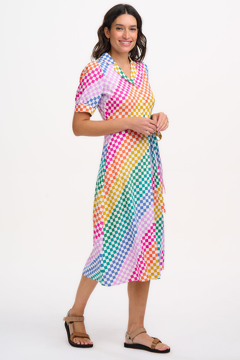 A model wearing a midi length shirt dress with a rainbow checkerboard pattern, featuring a lapel collar and puff sleeves.