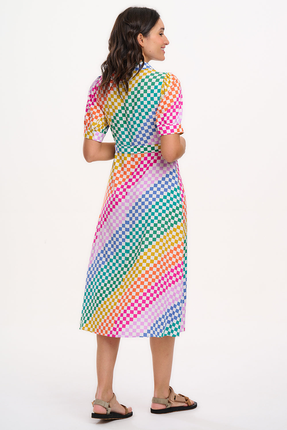 A model wearing a midi length shirt dress with a rainbow checkerboard pattern, featuring a lapel collar and puff sleeves.