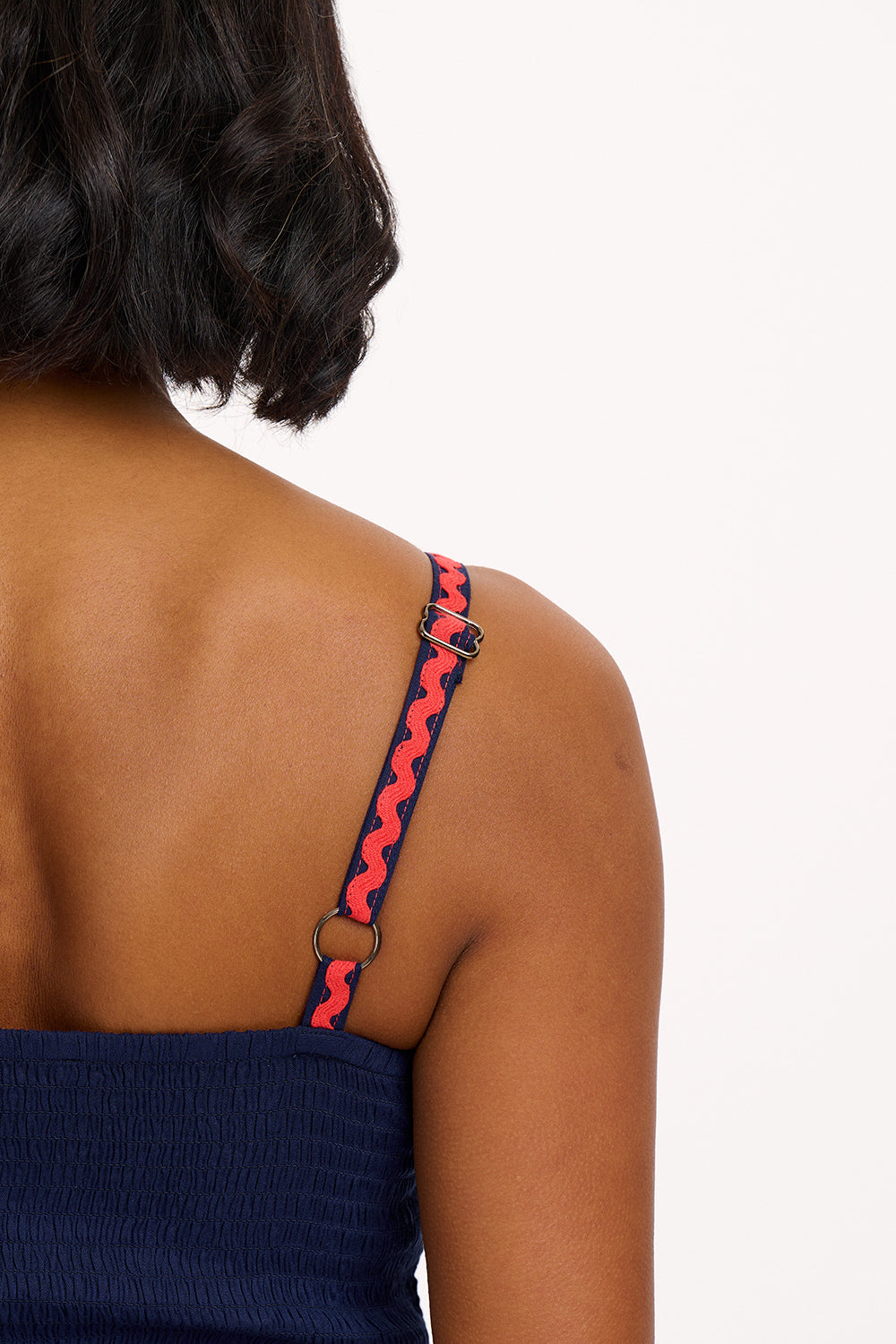 A model wearing a navy sundress with rainbow-colored Ric Rac embellishments on the hem and shoulder straps