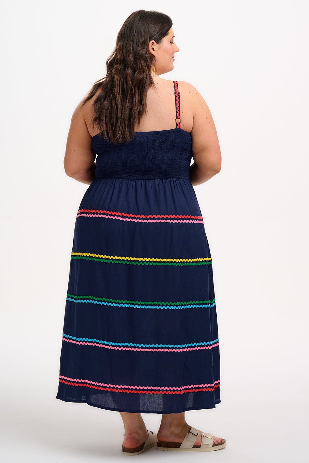 A model wearing a navy sundress with rainbow-colored Ric Rac embellishments on the hem and shoulder straps