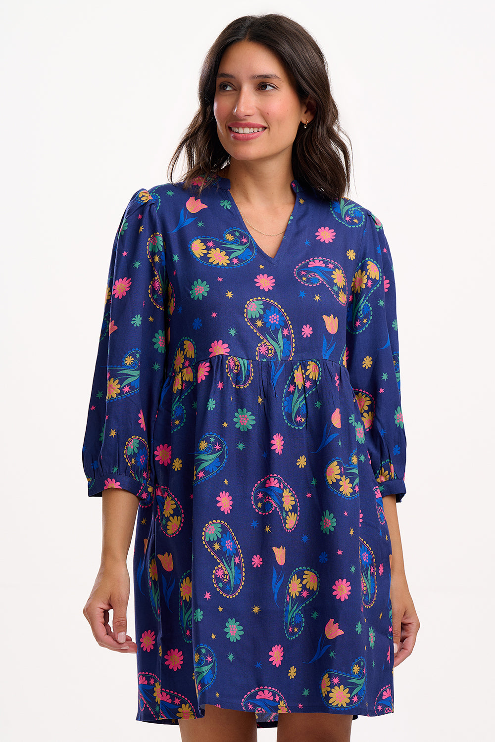 Sugarhill Brighton model wearing a blue dress with colourful floral patterns on a white background