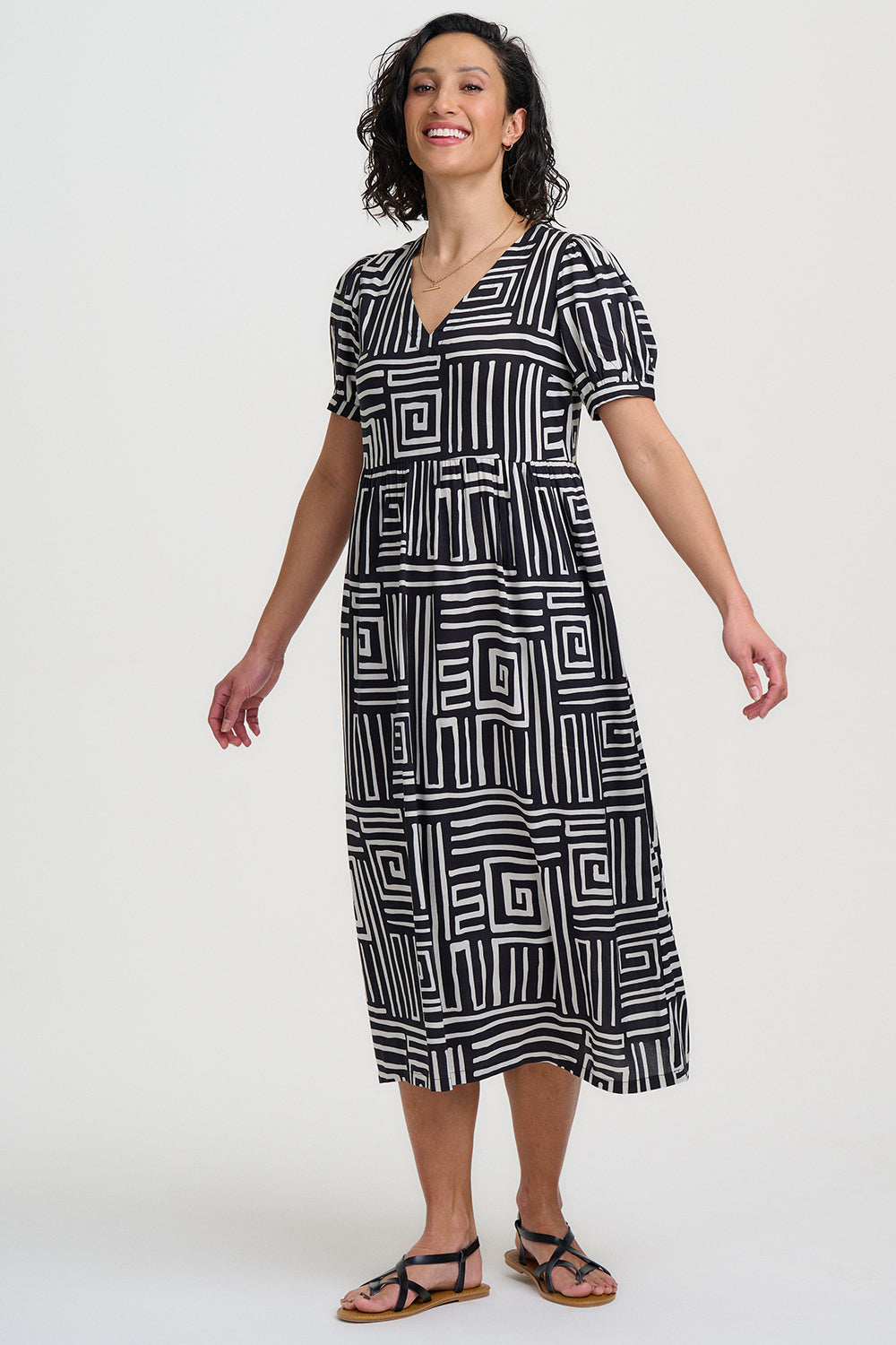 Woman wearing a black and white geometric patterned dress on a white background