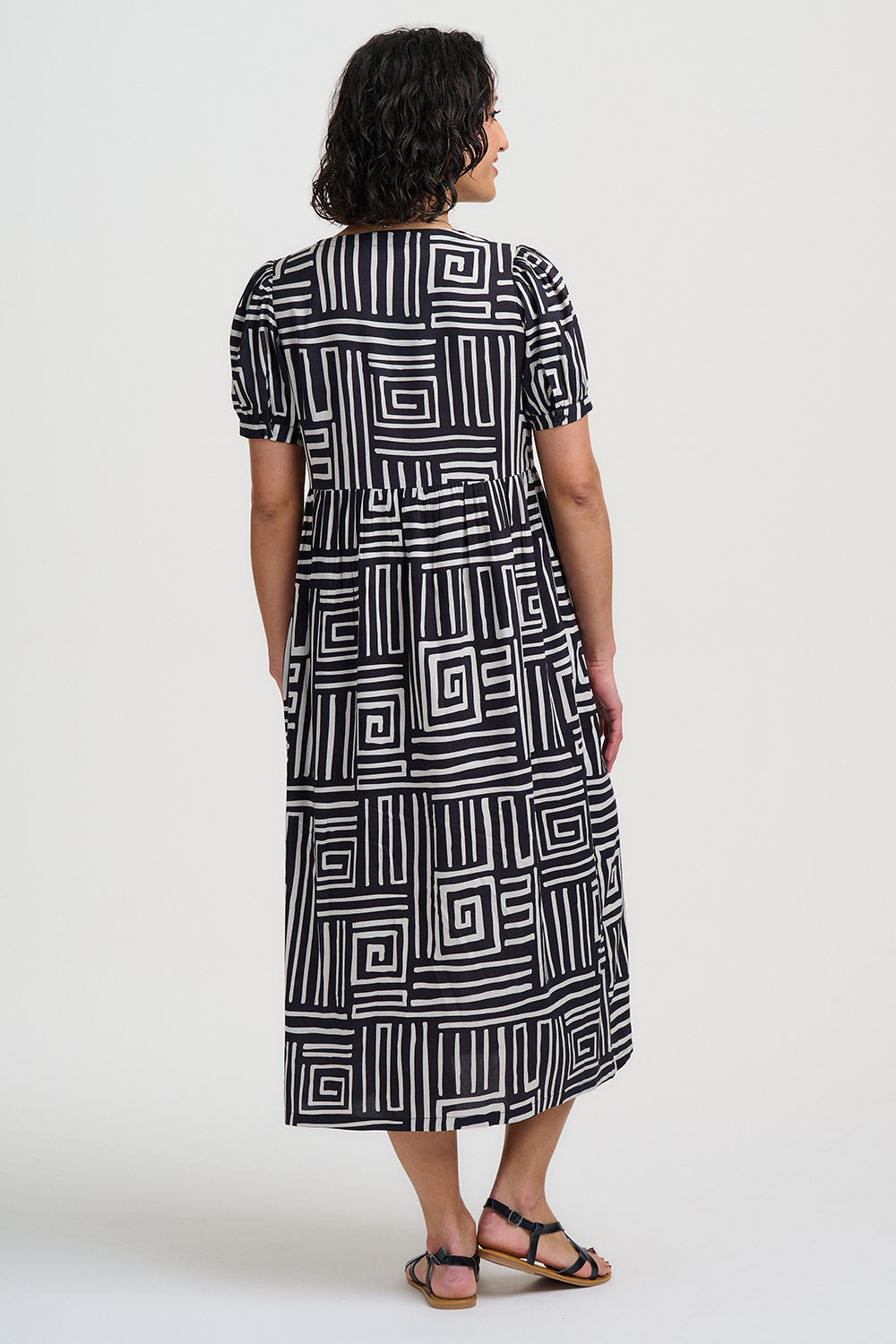 Woman wearing a black and white patterned dress on a white background