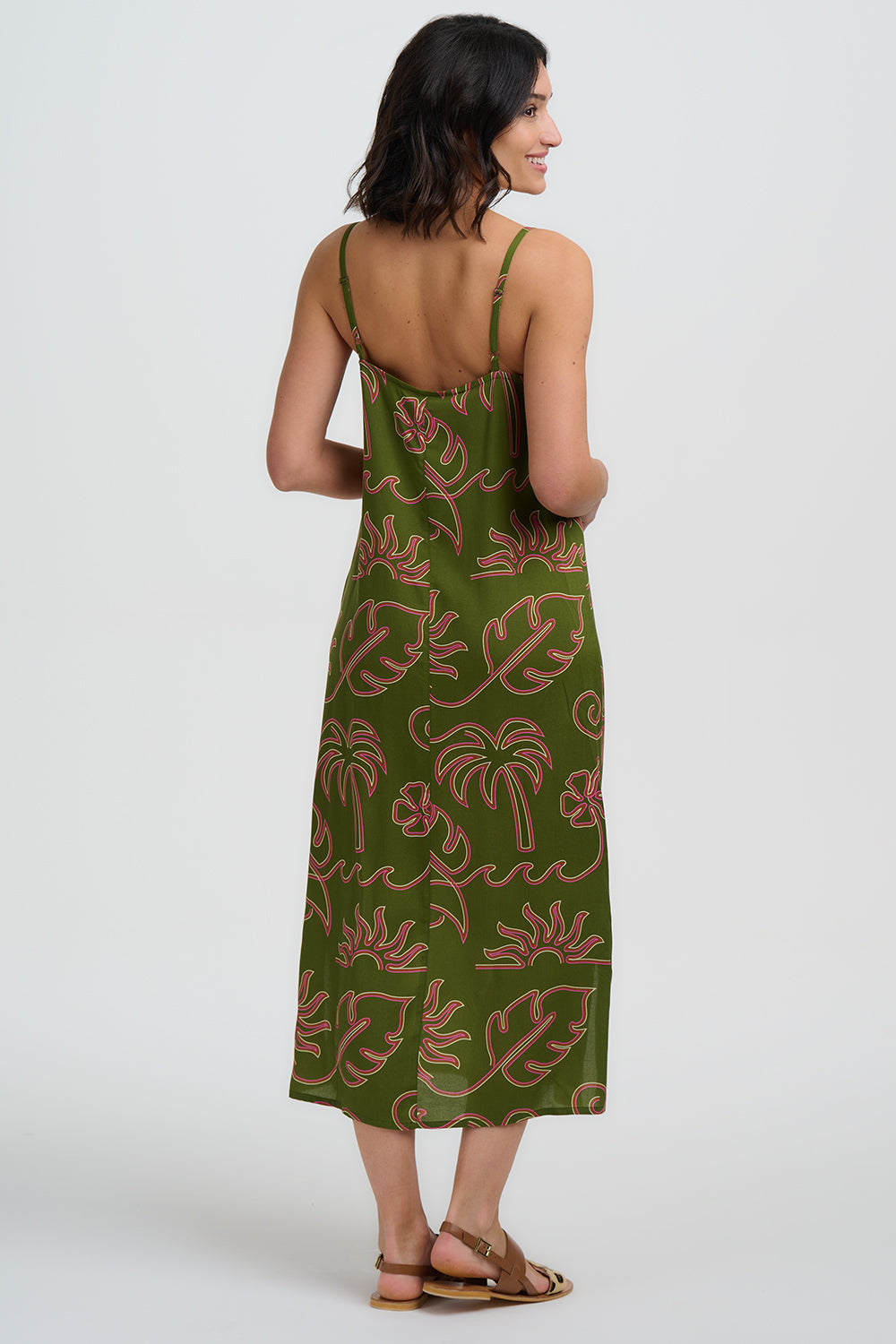 Woman wearing a green dress with palm tree pattern on a white background