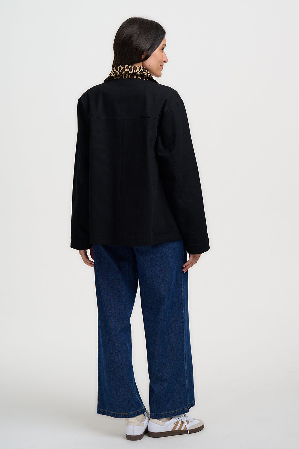Person wearing a black jacket and blue jeans on a white background