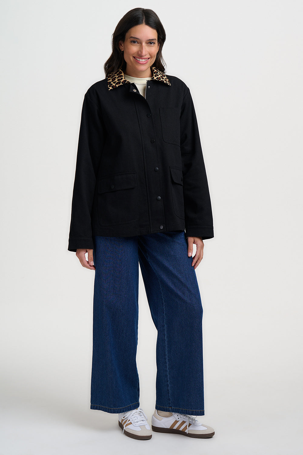 Person wearing a black jacket and blue jeans on a white background