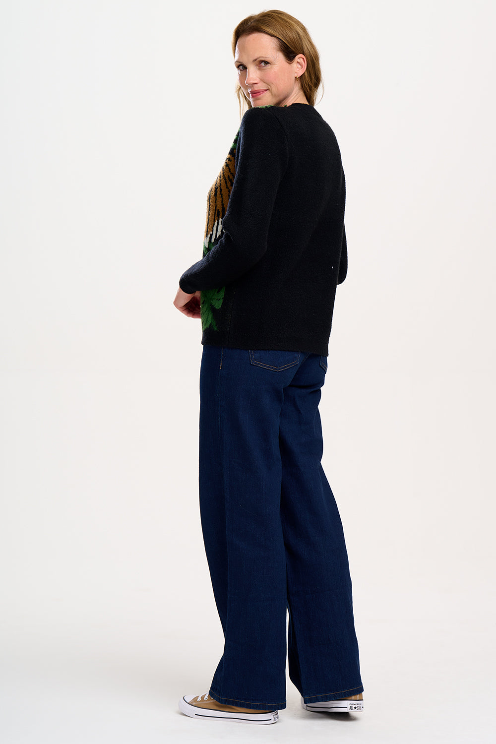 A woman  wearing a black, tiger, and palm design jumpers with a crew neck and long sleeves.