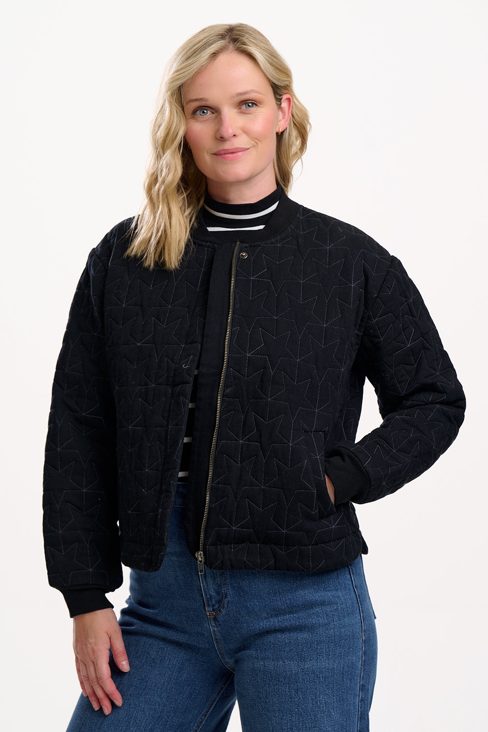 Woman wearing a black quilted jacket with a white background