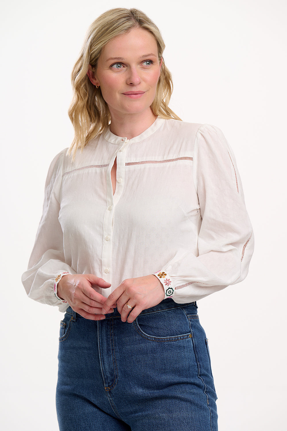 Woman wearing a white blouse and blue jeans on a white background