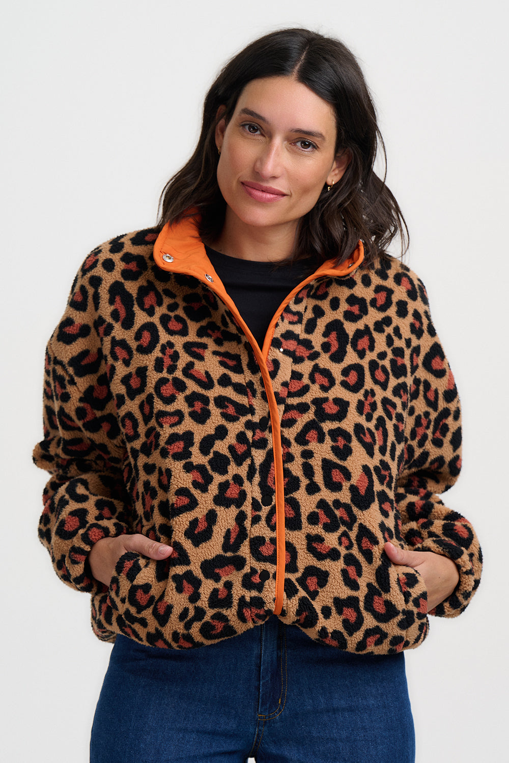 Woman wearing a leopard print jacket with orange zipper on a white background