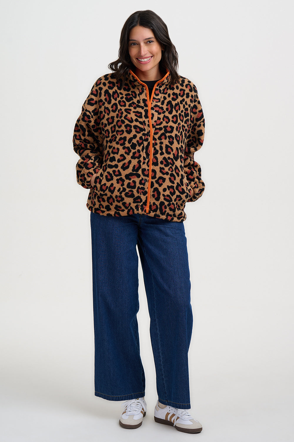 Woman wearing a leopard print jacket and blue pants on a white background