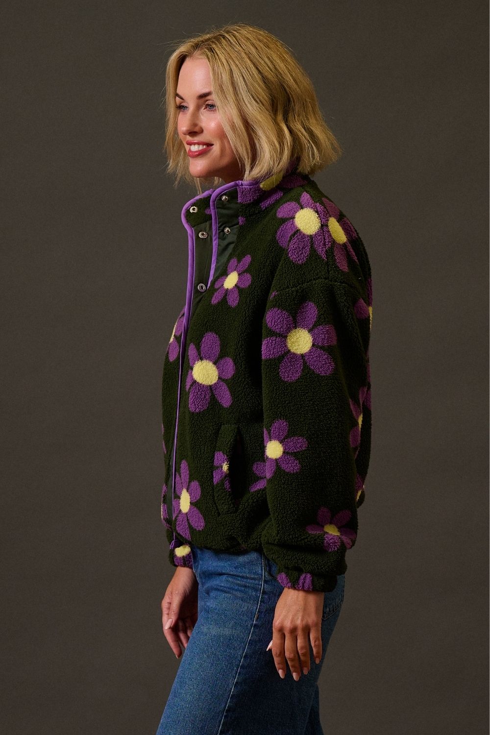 Woman wearing a black jacket with purple floral patterns on a dark background