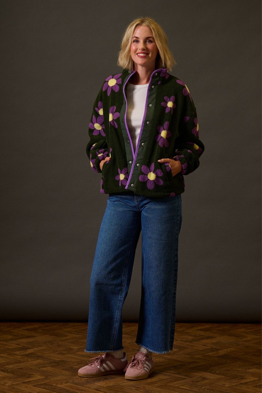 Woman wearing a black jacket with purple floral patterns against a dark background