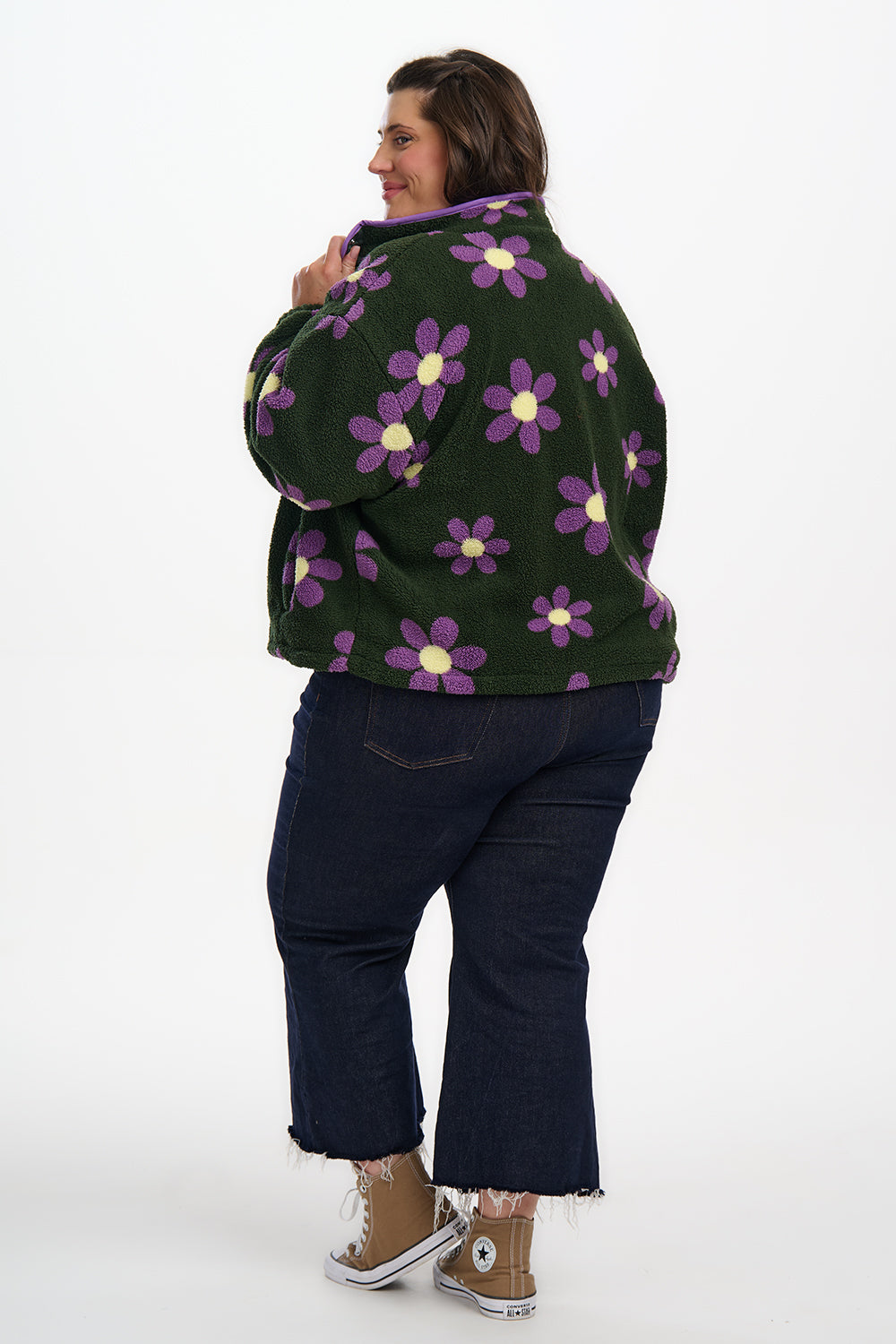 Person wearing a green jacket with purple floral patterns on a white background