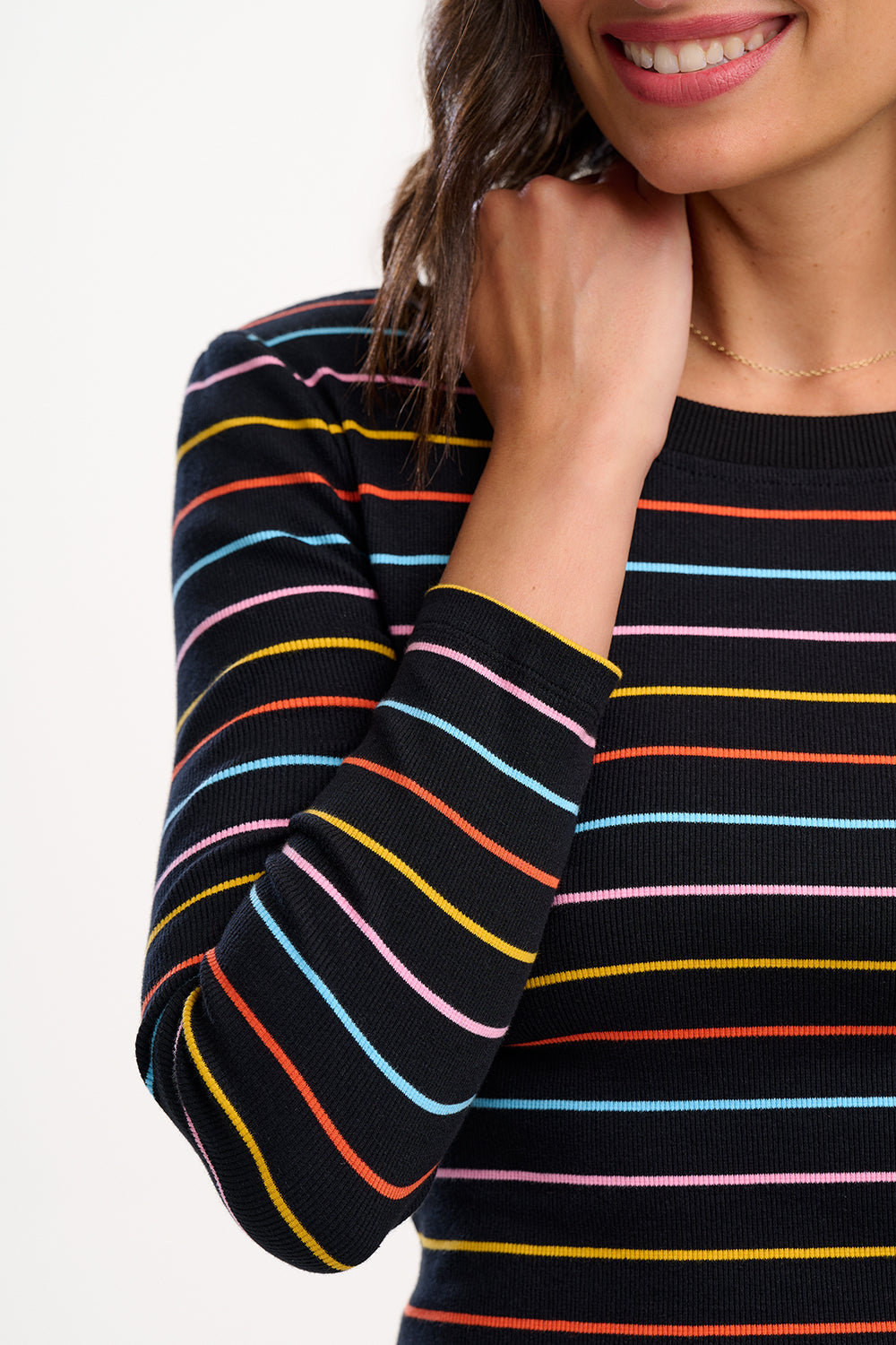 Close-up of a person wearing a black sweater with colorful stripes on a white background