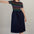 Sugarhill Brighton model wearing a black dress with colourful stripes and pink shoes against a plain background