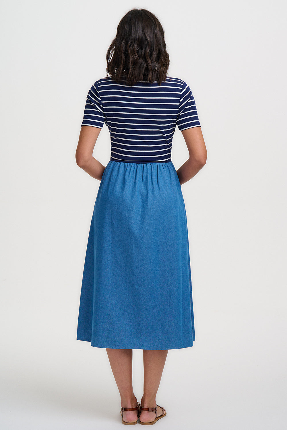 Person wearing a blue and white striped shirt and blue skirt on a white background