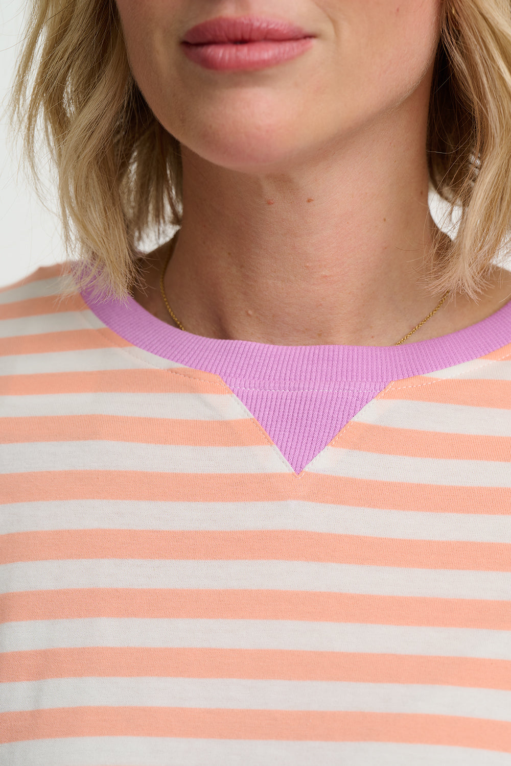 Close-up of a person wearing a striped shirt with a purple neckline.