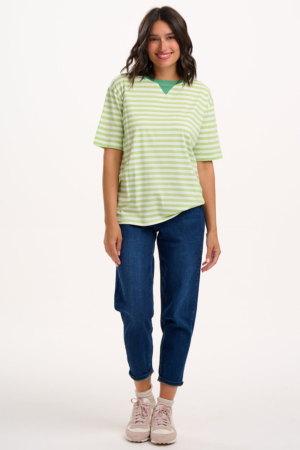 Sugarhill Brighton model wearing a green and white striped shirt and blue jeans on a white background