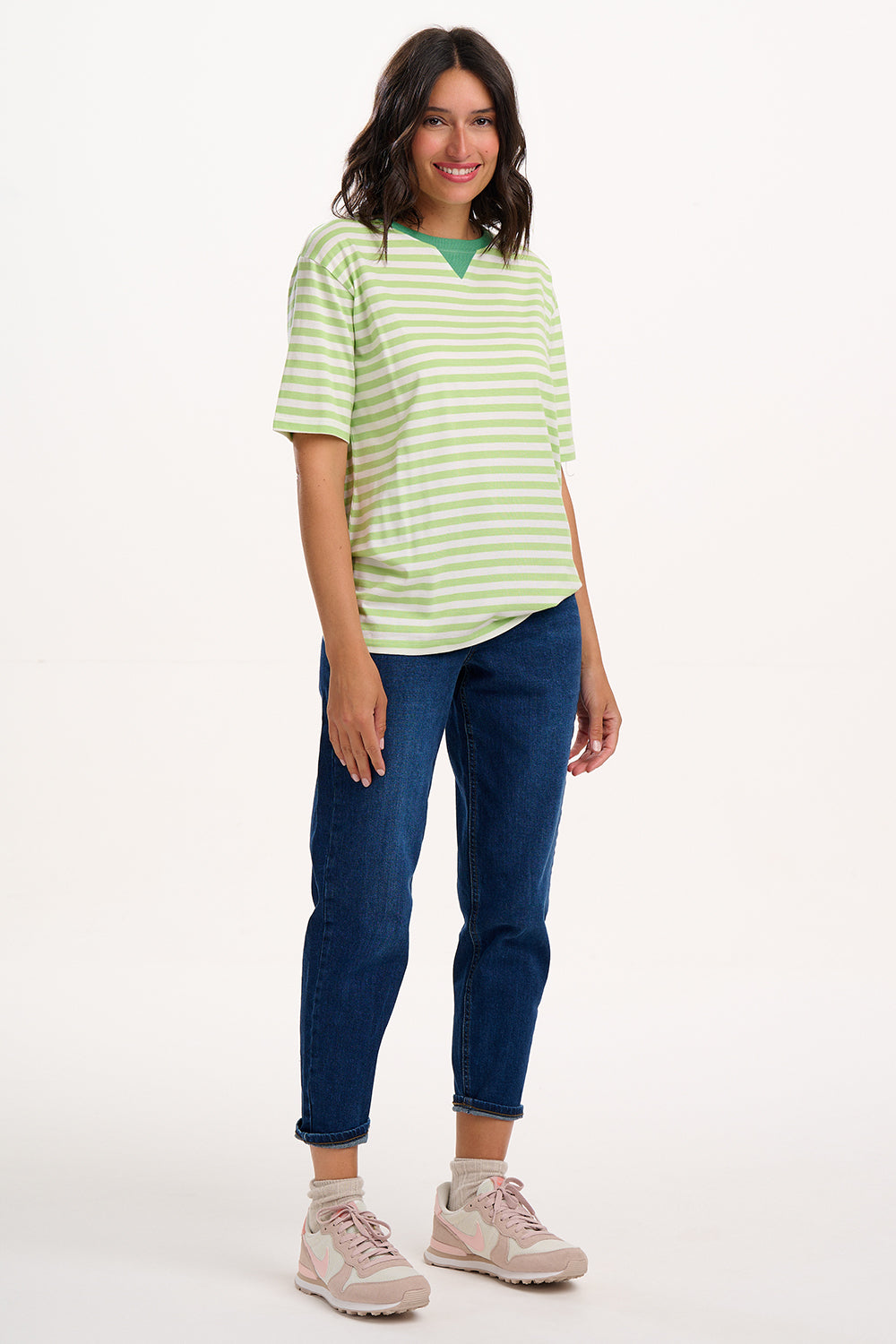 Sugarhill Brighton model wearing a green and white striped shirt and blue jeans on a white background