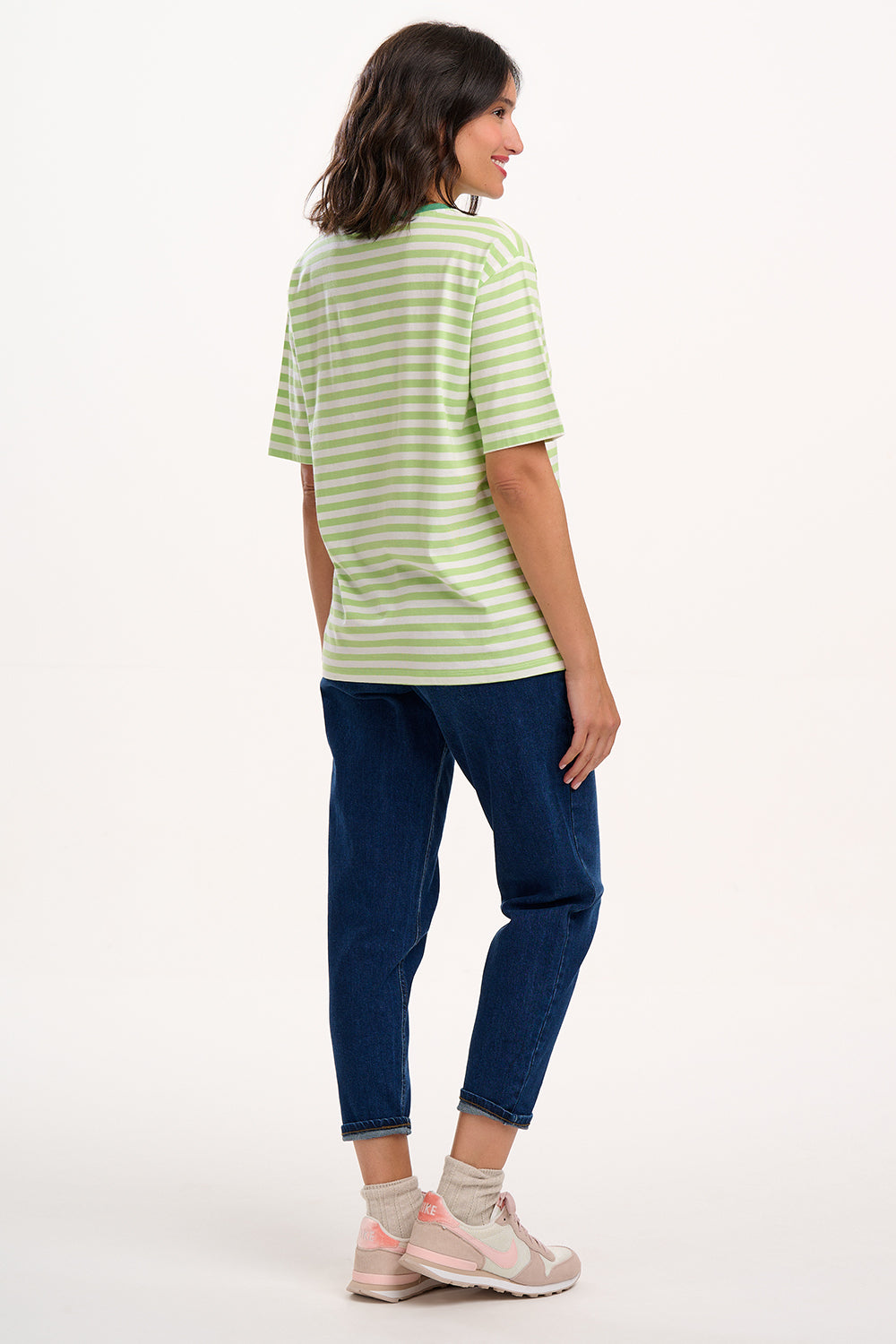 Sugarhill Brighton model wearing a green and white striped shirt and blue jeans on a white background