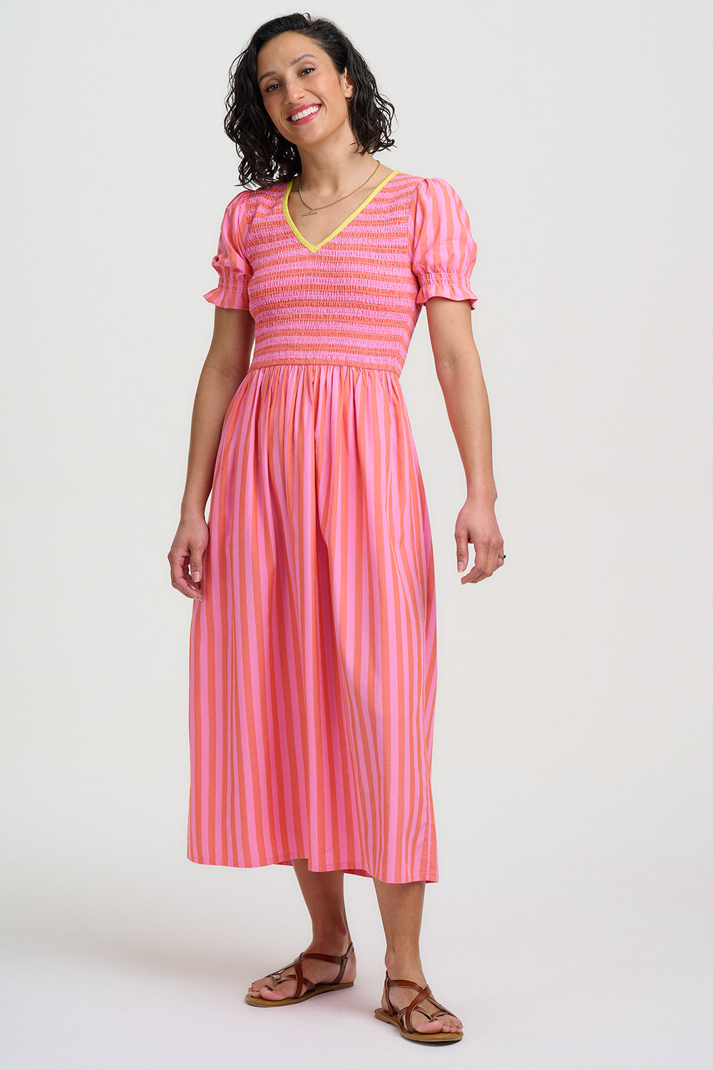 Woman wearing a pink and orange striped dress on a white background