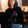 Person wearing a black sweater with a cat design, sitting indoors.
