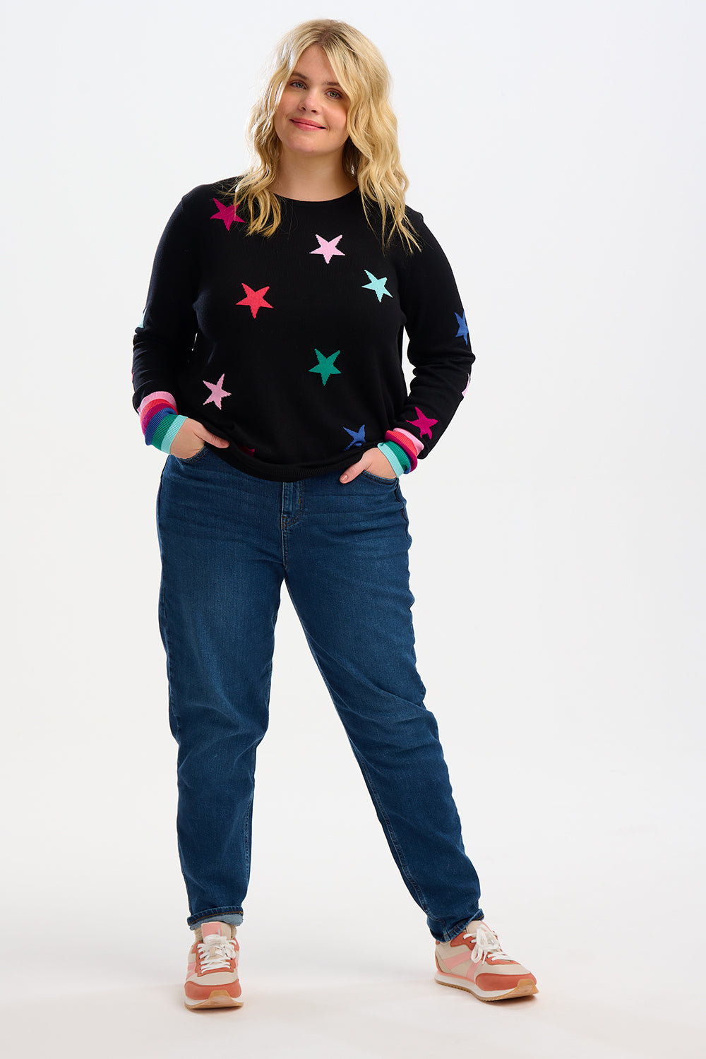 model wearing a black jumpoer with stars on and rainbow cuffs 