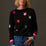 Woman wearing a black sweater with colorful star patterns against a dark background