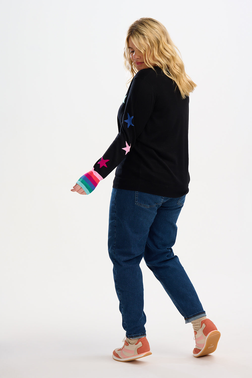 model wearing a black jumpoer with stars on and rainbow cuffs 